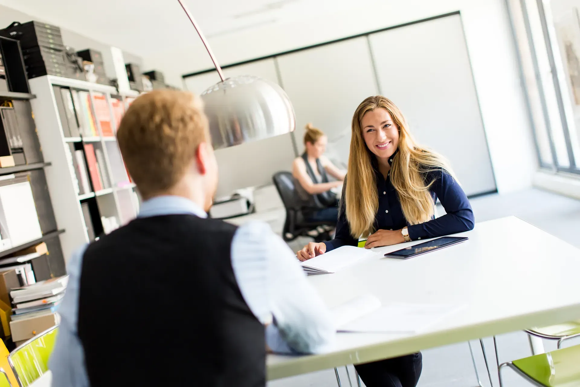 Beratungsgespräch zwischen einem Mann und einer Frau an einem Tisch im hellen Büro